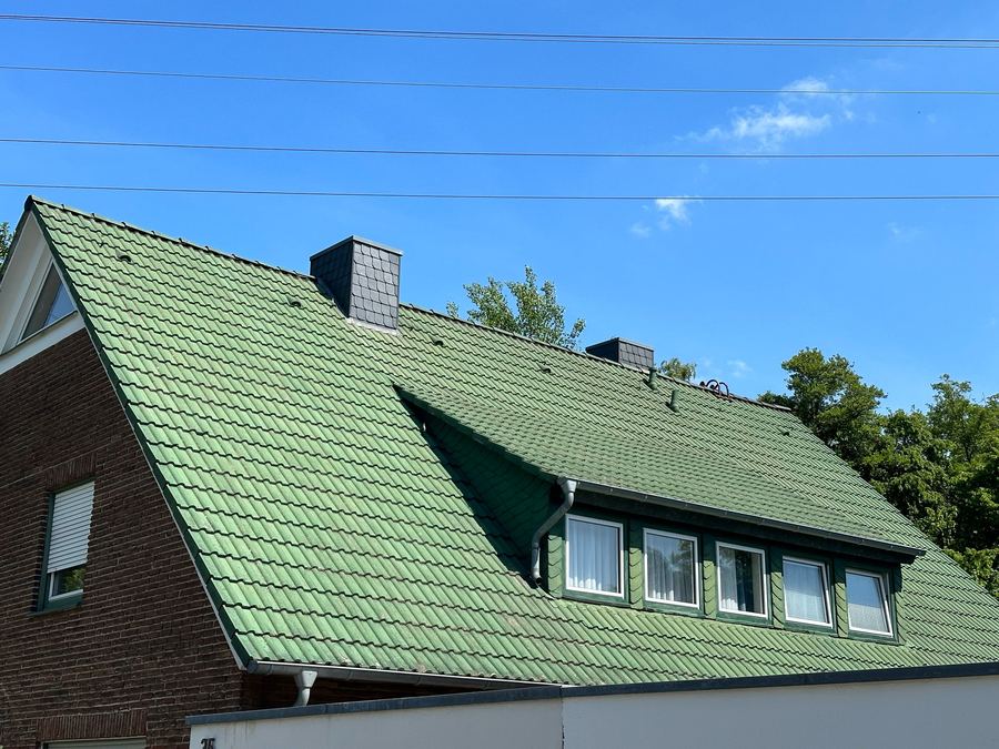 Stark bemoostes grünes Ziegeldach eines Hauses in Münster vor der Dachreinigung